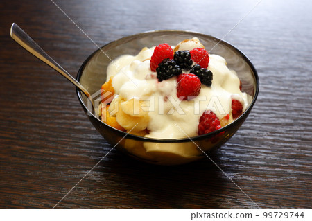 Fresh delicious fruit salad with yogurt on a wooden table 99729744