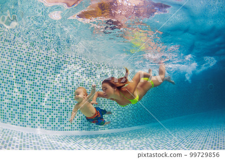 Mother, father with baby swimming, diving underwater in pool 99729856