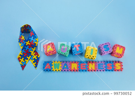 Word Autism Awareness day. Autism Awareness Ribbon and Puzzle cubes on blue background. 99730052