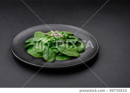 Fresh green spinach leaves on a black ceramic plate 99730810