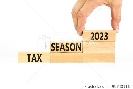 Tax season 2023 symbol. Concept words Tax season 2023 on wooden blocks on a beautiful white table white background. Businessman hand. Business Tax season 2023 concept. Copy space. Tax season 2023 symbol. Concept words Tax season 2023 on wooden blocks on a beautiful white table white background. Businessman hand. Business Tax season 2023 concept. Copy space. 99730918
