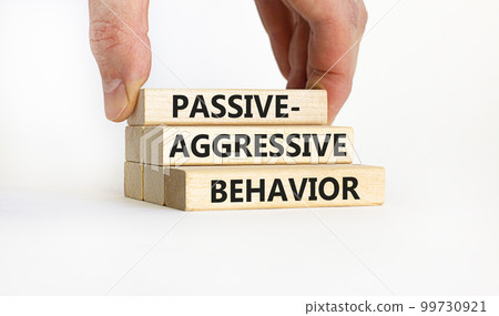 Passive-aggressive behavior symbol. Concept words Passive-aggressive behavior on wooden blocks. Businessman hand. Beautiful white background. Business, Passive-aggressive behavior concept. Copy space. 99730921