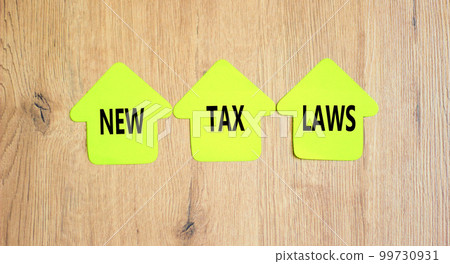 New tax laws symbol. Concept words New tax laws on green paper houses on a beautiful wooden table wooden background. Business new tax laws concept. Copy space. New tax laws symbol. Concept words New tax laws on green paper houses on a beautiful wooden table wooden background. Business new tax laws concept. Copy space. 99730931