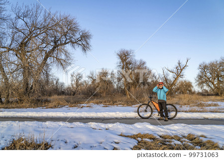 senior cyclist with a mountain bike is taking a rest stop on Poudre River Trail near Greeley, Colorado, in winter scenery senior cyclist with a mountain bike is taking a rest stop on Poudre River Trail near Greeley, Colorado, in winter scenery 99731063