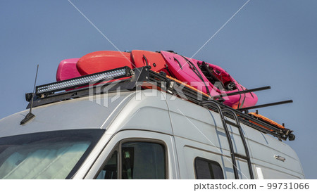 Whitewater kayaks on roof racks of a camper van Whitewater kayaks on roof racks of a camper van 99731066