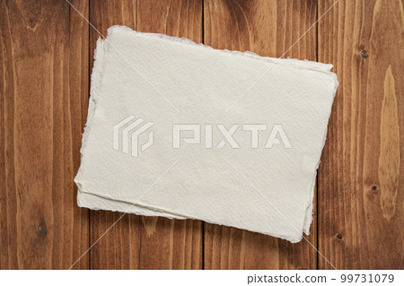 small sheet of blank white Khadi rag paper against rustic wood background 99731079