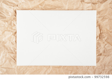 Background image crumpled recycled textured kraft paper with sheet of white cardboard in middle. Top view. Copy space Background image crumpled recycled textured kraft paper with sheet of white cardboard in middle. Top view. Copy space 99732598