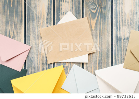 White open envelope with open kraft paper card on gray wooden background. Multicolored envelopes lie by side. Copy space White open envelope with open kraft paper card on gray wooden background. Multicolored envelopes lie by side. Copy space 99732613