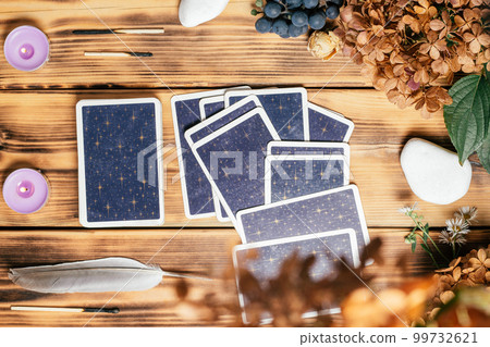 Tarot cards spread face down on wooden surface with candles, stones, autumn plants. Minsk, Belarus, 11.10.2021 99732621