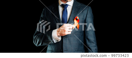 Aid ribbon silk. Red ribbon in hiv world day in man hand. Awareness aids and cancer symbol on black background. HIV, AIDS and aging awareness month with copy space. Aid ribbon silk. Red ribbon in hiv world day in man hand. Awareness aids and cancer symbol on black background. HIV, AIDS and aging awareness month with copy space. 99733423