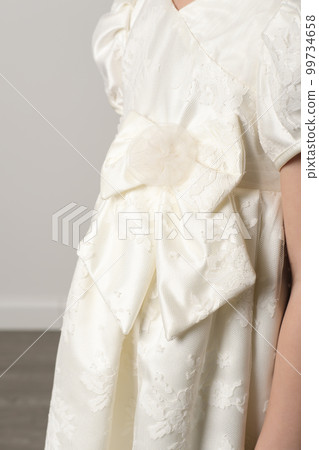 details of white satin lace braidsmaid dress. flower girl goan with large fabric bow. vertical details of white satin lace braidsmaid dress. flower girl goan with large fabric bow. vertical 99734658