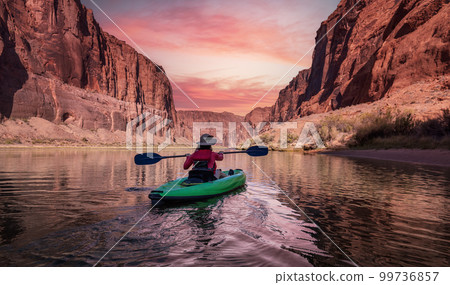 Adventurous Woman on a Kayak paddling in Colorado River. Glen Canyon, Arizona, USA. Adventurous Woman on a Kayak paddling in Colorado River. Glen Canyon, Arizona, USA. 99736857