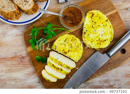 Sliced homemade cheese with spices on natural wooden board. Lithuanian traditional cheese 99737103