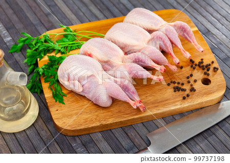Raw quails on wooden cutting board 99737198