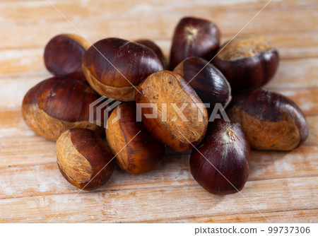 Unpeeled edible sweet chestnuts on wooden background Unpeeled edible sweet chestnuts on wooden background 99737306