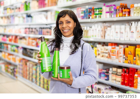 Adult Latina choosing haircare cosmetics in specialized boutique 99737353