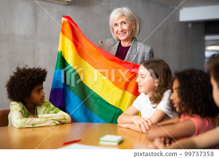 Female teacher showing rainbow flag to kids in geography class Female teacher showing rainbow flag to kids in geography class 99737358
