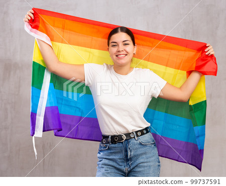 Happy girl stands with flag of LGBT. Isolated on gray background 99737591