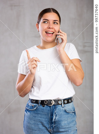Cheerful young woman talking on mobile phone 99737640