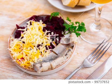 Sliced herring with grated beetroot and cheese served on table 99737652
