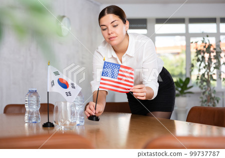 Young female attendant putting up flags for international negotiations between south korea and usa Young female attendant putting up flags for international negotiations between south korea and usa 99737787