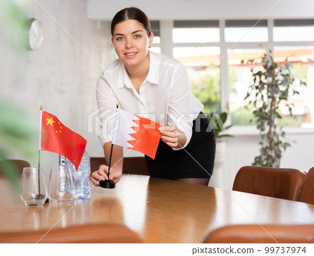 Young female attendant putting up flags for international negotiations between china and bahrain Young female attendant putting up flags for international negotiations between china and bahrain 99737974