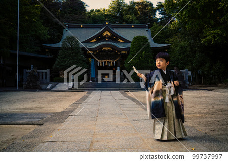 A figure of a 5-year-old child who came to visit the shrine of Shichi-go-san in Japanese clothes poses with the main building in the background in the precincts of the shrine A figure of a 5-year-old child who came to visit the shrine of Shichi-go-san in Japanese clothes poses with the main building in the background in the precincts of the shrine 99737997