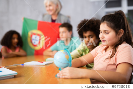 Female teacher showing portuguese flag to kids in geography class Female teacher showing portuguese flag to kids in geography class 99738018