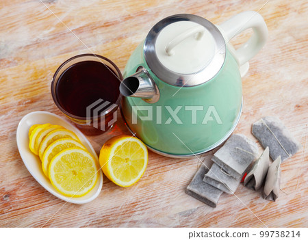 Electric kettle, cup of tea and lemon on wooden table Electric kettle, cup of tea and lemon on wooden table 99738214