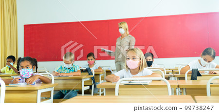 Focused kids in masks working at class Focused kids in masks working at class 99738247