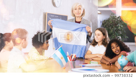 Female teacher showing argentinian flag to kids in geography class 99738332
