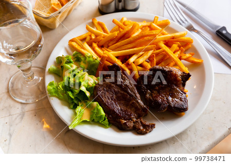 Tasty beef steak slices with French fries and salad Tasty beef steak slices with French fries and salad 99738471