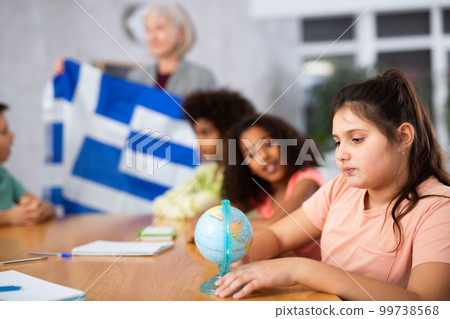 Female teacher showing greek flag to kids in geography class 99738568