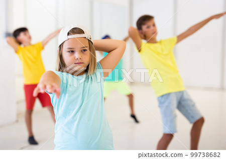 Girl together with other children, learns modern hip hop dance moves in class Girl together with other children, learns modern hip hop dance moves in class 99738682