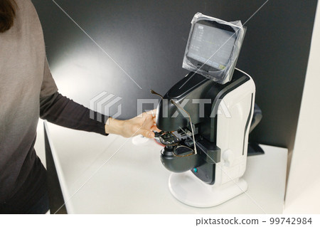 Focus on a special optical equipment. Optician checking eyeglasses in special machine. New ophthalmological technology. 99742984