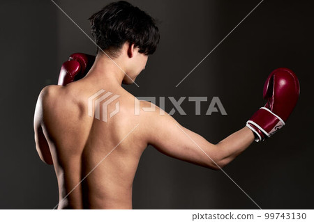 Rear view of a young man wearing boxing gloves 99743130
