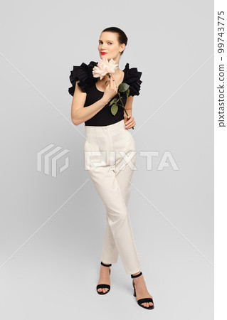 Adult woman holds flower in hand and looking to the side Adult woman holds flower in hand and looking to the side 99743775