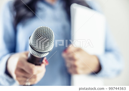Investigative journalist with microphone in other hand notebook - Close up Investigative journalist with microphone in other hand notebook - Close up 99744363