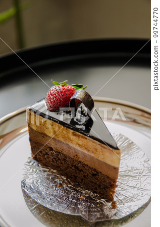 piece of brownie cheesecake with strawberry and chocolate on top 99744770