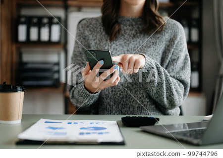Confident businesswoman working on laptop,tablet and tablet at her workplace at modern office.. Confident businesswoman working on laptop,tablet and tablet at her workplace at modern office.. 99744796