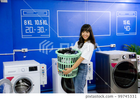 Asian girl is holding basket in laundry shop with smile face Asian girl is holding basket in laundry shop with smile face 99745331