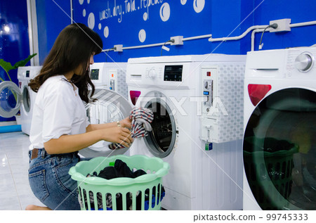 Asian girl is washing cloths by washing machine in laundry shop Asian girl is washing cloths by washing machine in laundry shop 99745333