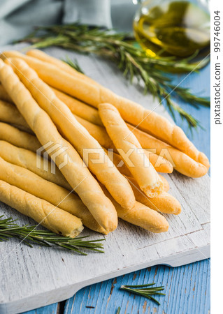 Italian grissini bread sticks on blue table. 99746004