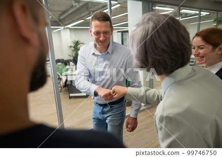 Caucasian man bumping his fists with colleagues as a sign of success.  99746750