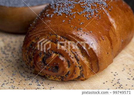Poppy seeds and a bun with poppy seeds on the table Poppy seeds and a bun with poppy seeds on the table 99749571