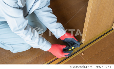 Image of a worker repairing and inspecting a sliding door roller Image of a worker repairing and inspecting a sliding door roller 99749764
