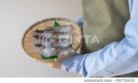 A man wearing an apron with a fillet of cod A man wearing an apron with a fillet of cod 99750410