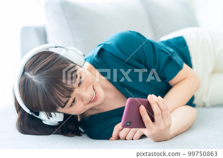 Woman, smartphone, headphones, relaxing, lifestyle, living room Woman, smartphone, headphones, relaxing, lifestyle, living room 99750863