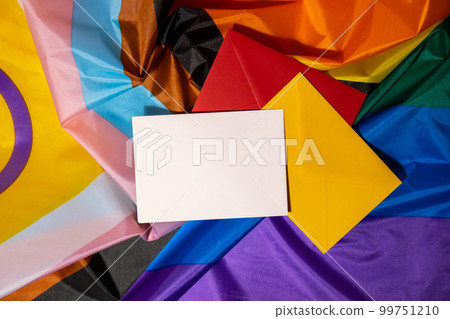Empty paper blank on Rainbow LGBTQIA flag made from silk material. Mock up template copy space for your text. Symbol of LGBTQ pride month. Equal rights. Peace and freedom. Support LGBTQIA community 99751210