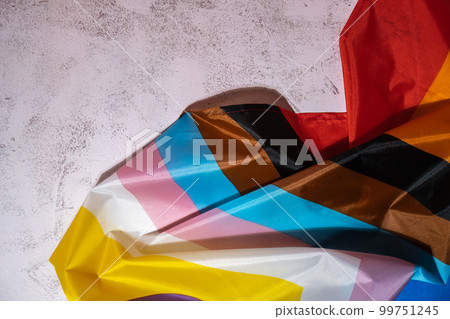 Rainbow LGBTQIA flag made from silk material on concrete background with copy space for your text. Valentine's Day greeting card. Symbol of LGBTQ pride month. Equal rights. Peace and freedom. Support 99751245